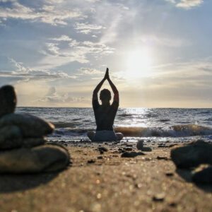 A woman doing yoga at a beach during the day